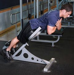 Man performing triceps dips on a gym machine, focusing on exercise.
